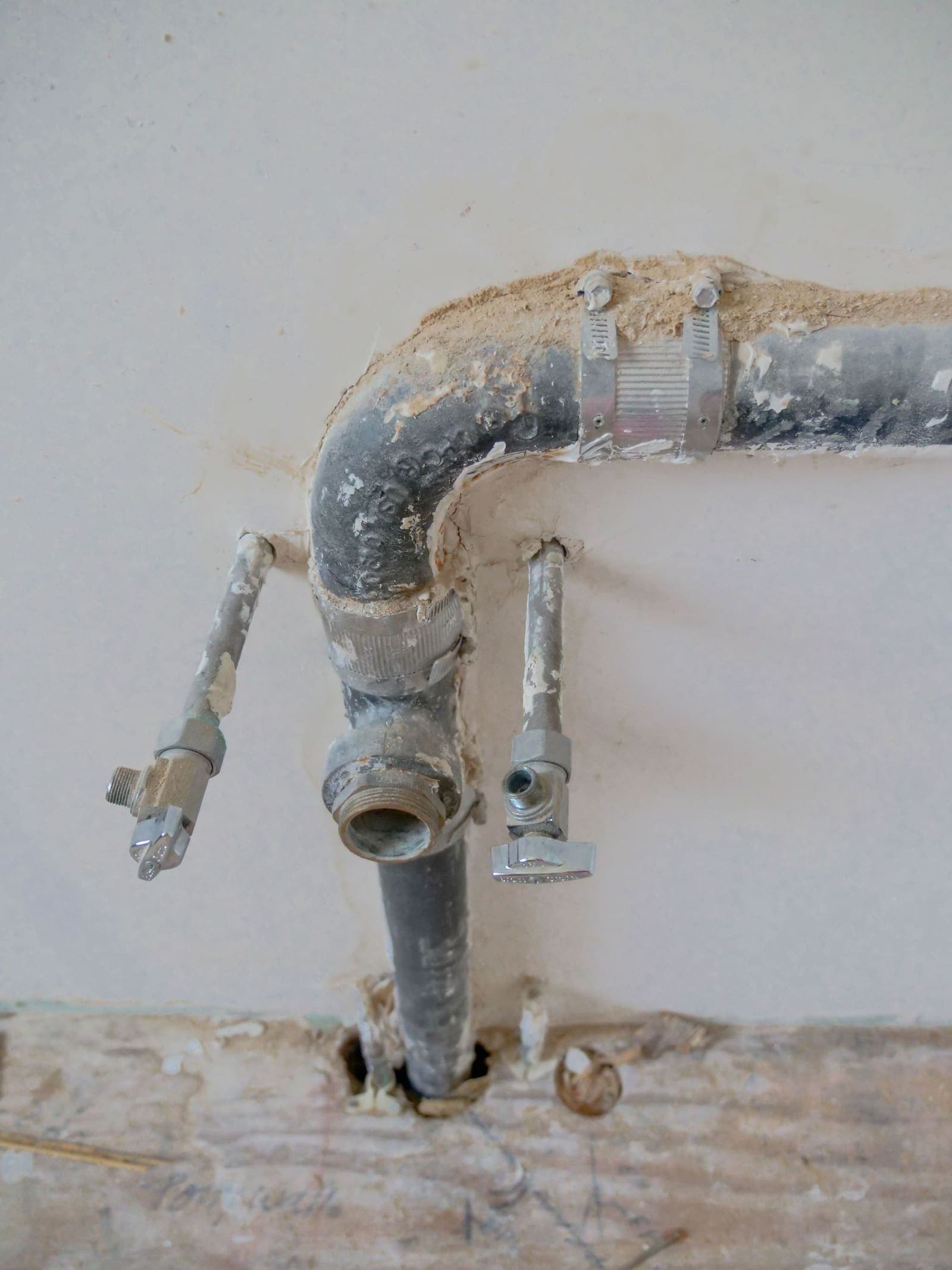 Old metal water and drain pipes exposed in an opened wall