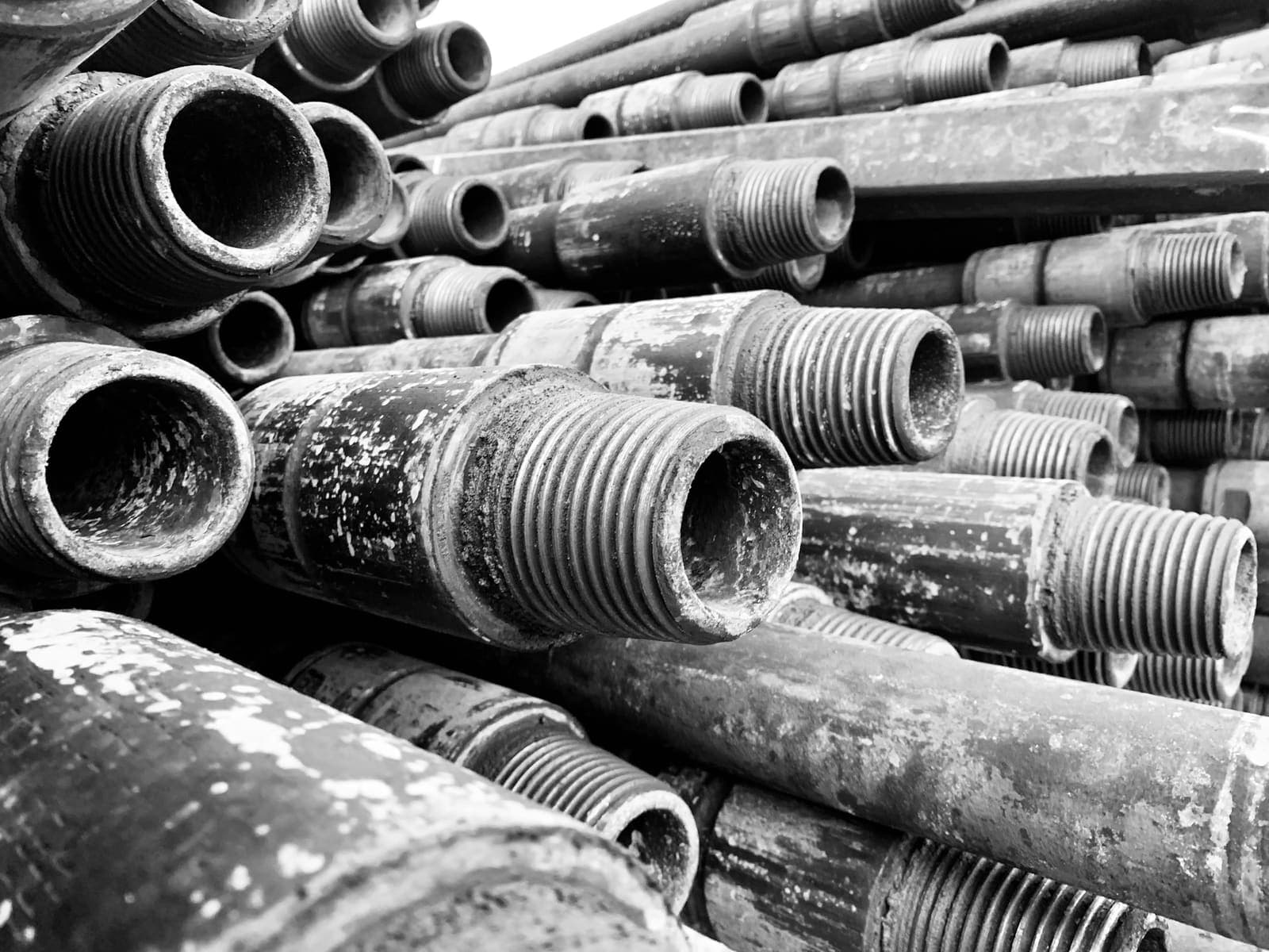 A pile of old steel pipe with threaded ends