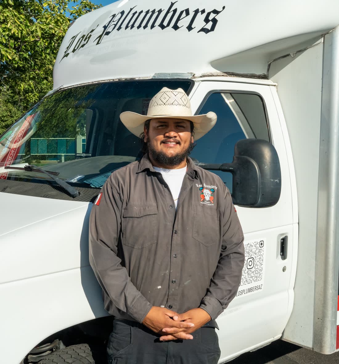 Un plomero de Los Plumbers parado frente a una camioneta de servicio con el logo de la empresa en Mesa
